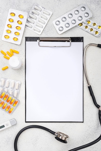 Flat lay medical desk composition with empty clipboard