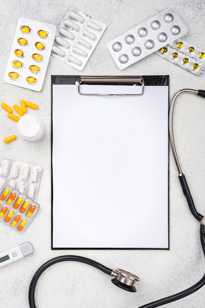 Flat lay medical desk composition with empty clipboard