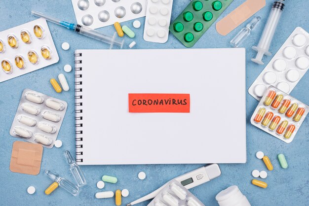 Flat lay medical elements composition with coronavirus tag on notepad