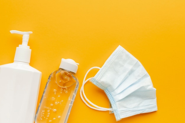 Flat lay of medical mask with liquid bottle and hand sanitizer