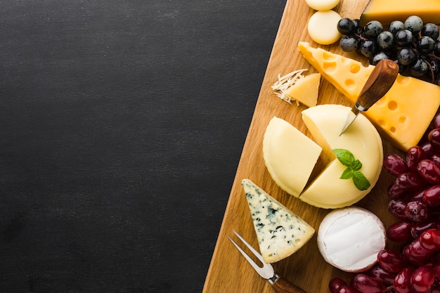 Flat lay mix of gourmet cheese and grapes on cutting board with copy space