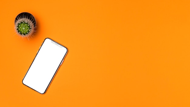 Бесплатное фото Плоский лежал макет смартфона с оранжевым фоном