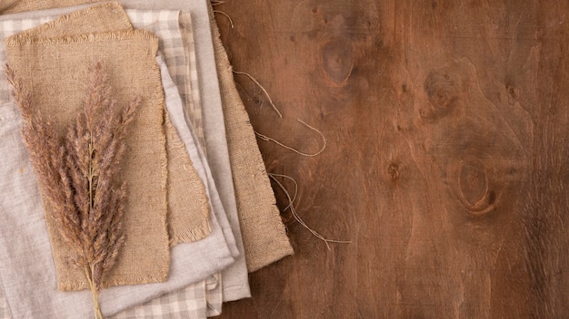 Free photo flat lay of monochromatic selection of textiles with dried grass and copy space