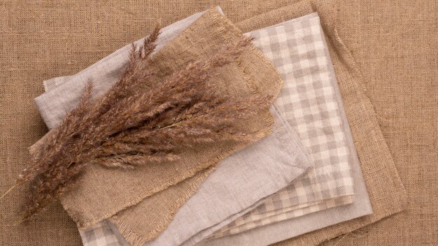 Flat lay of monochromatic selection of textiles with dried grass