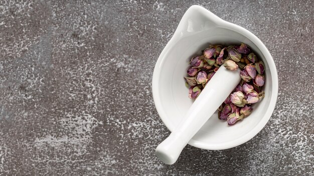 Flat lay of mortar and pestle with rose buds and copy space