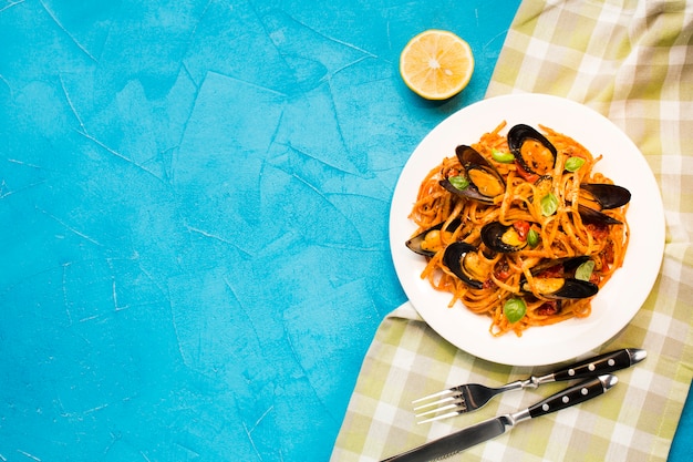 Flat-lay mussel pasta on tablecloth with copyspace