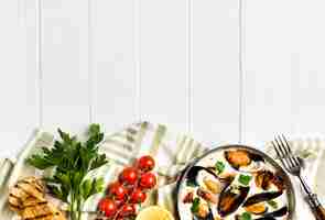 Free photo flat-lay mussels in white sauce and sides on tablecloth with copyspace