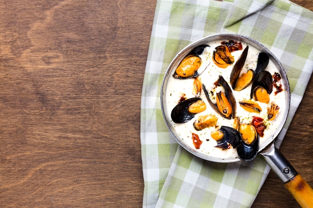 Flat-lay mussels in white sauce on tablecloth with copyspace