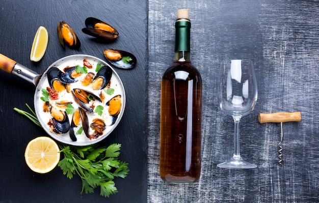 Flat-lay mussels in white sauce and wine bottle