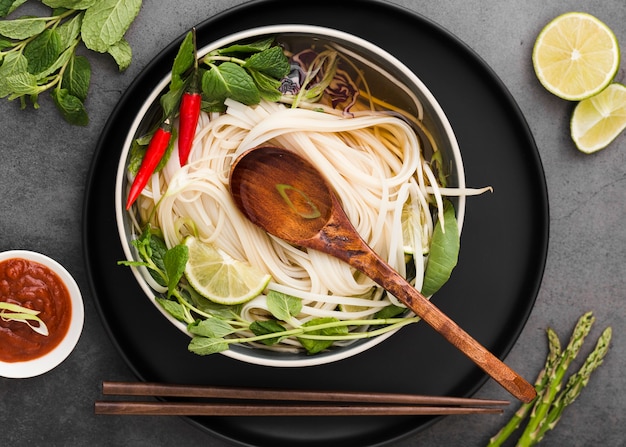 Flat lay of noodles in bowl with spoon and sauce