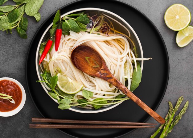 Flat lay of noodles in bowl with spoon and sauce