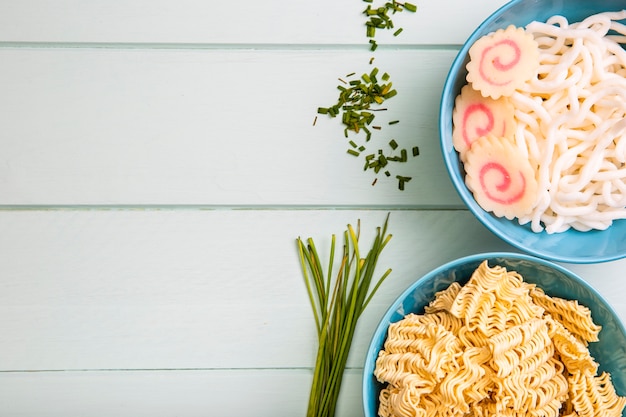 Flat lay noodles in bowls and chives with copy space