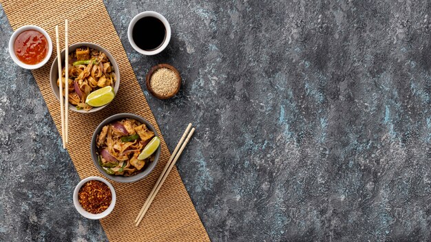 Flat lay noodles in bowls and sauces with copy space