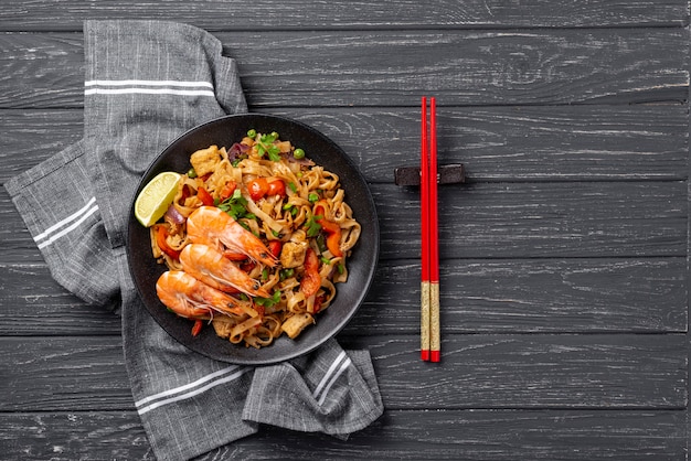 Flat lay noodles with vegetables and chicken with chopsticks