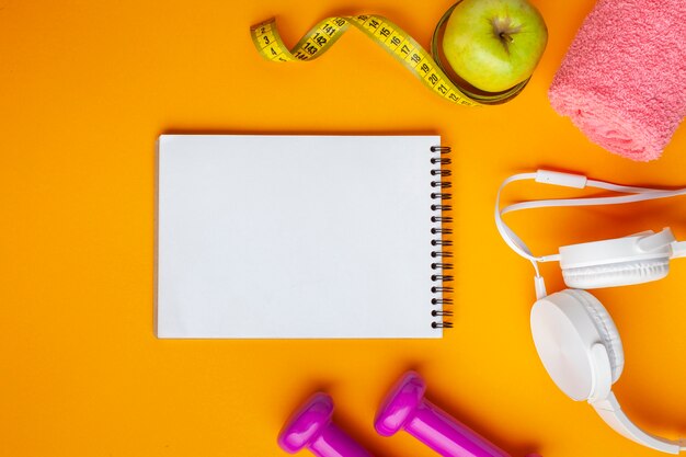 Flat lay notebook and apple on yellow background