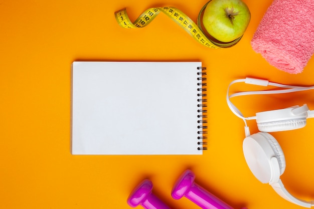 Flat lay notebook and apple on yellow background