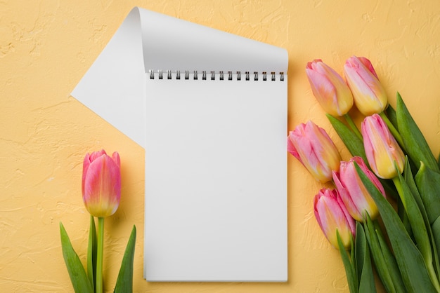 Flat lay notebook beside tulips