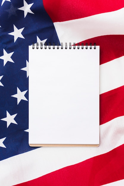 Flat lay of notebook on top of american flag