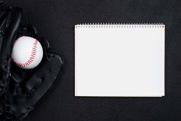 Flat lay of notebook with baseball in glove