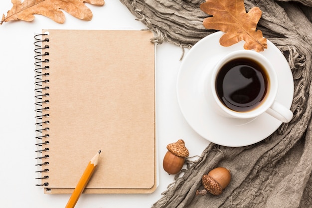 Flat lay of notebook with coffee and autumn leaves