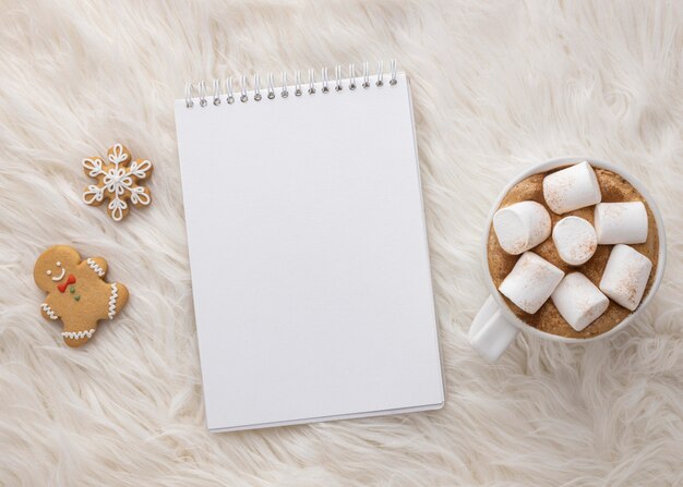 Flat lay of notebook with cup of hot cocoa with marshmallows