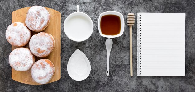 Flat lay of notebook with doughnuts and milk