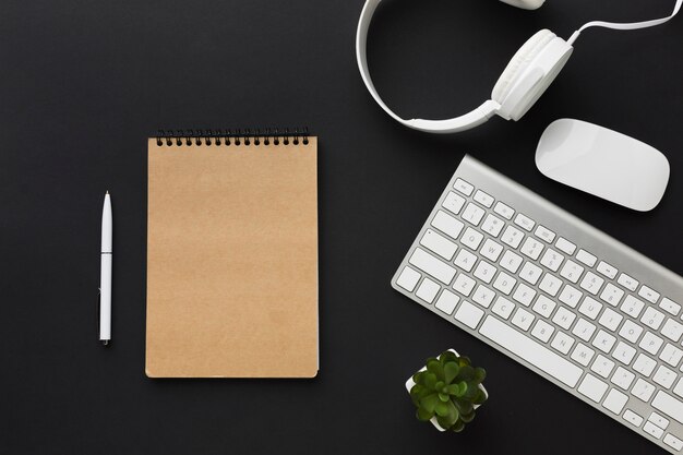 Flat lay of notebook with headphones on desktop