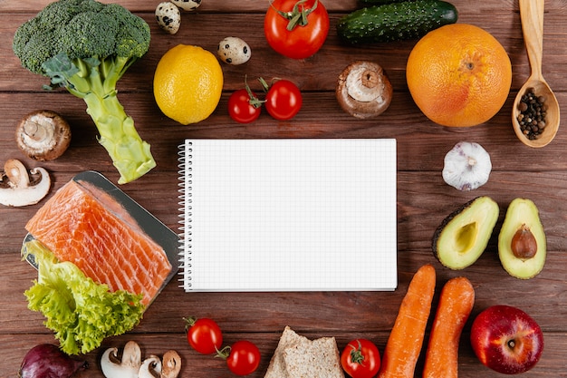 Flat lay of notebook with lots of vegetables and salmon