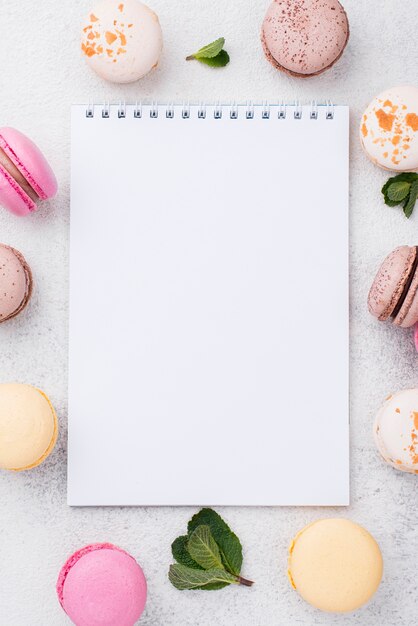 Flat lay of notebook with macarons and mint