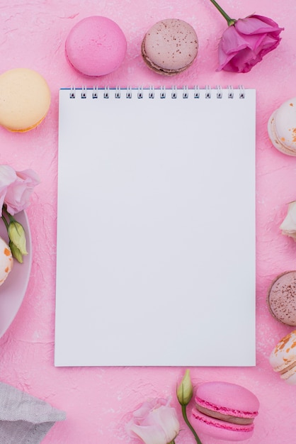 Free photo flat lay of notebook with macarons and roses