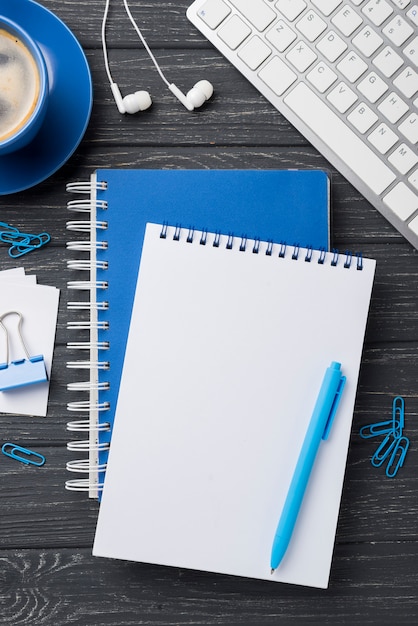 Flat lay of notebooks on wooden desk with headphones and coffee cup