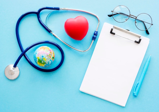 Flat lay of notepad with heart shape and stethoscope