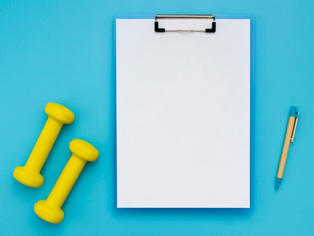 Flat lay of notepad with weights and pen