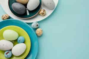 Бесплатное фото Плоская кладка цветных пасхальных яиц на нескольких тарелках