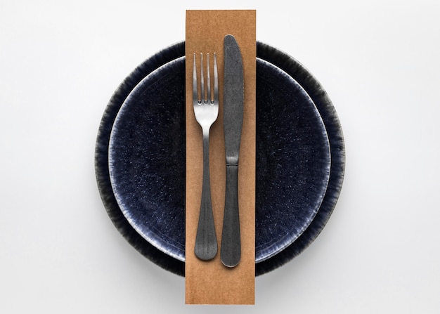 Бесплатное фото Плоская планировка темной посуды с вилкой и ножом