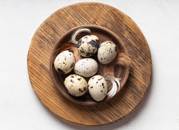 Бесплатное фото Плоская кладка пасхальных яиц на деревянной тарелке с перьями