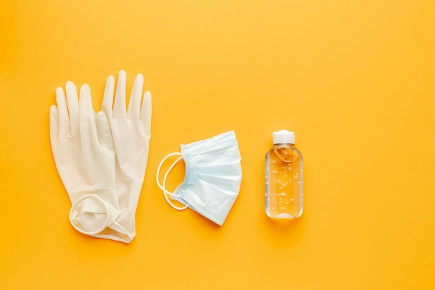 Бесплатное фото Плоская планировка перчаток с медицинской маской и дезинфицирующим средством для рук