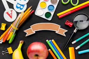 Бесплатное фото Плоская планировка школьных принадлежностей с фруктами и карандашами