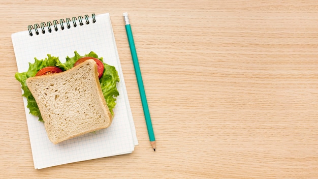 Плоская планировка школьных принадлежностей с блокнотом и бутербродом