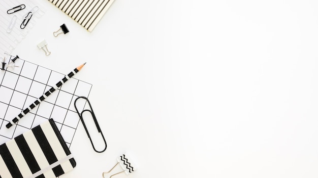 Flat lay of office stationery with pencil and paper clips