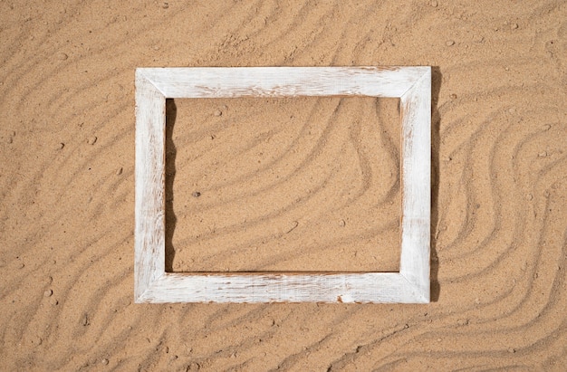 Flat lay old frame on sand