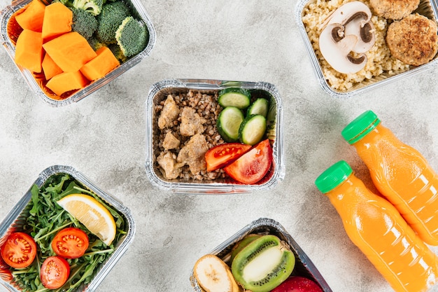 Flat lay of orange juice bottles with meals in casseroles