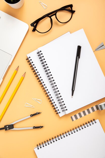 Flat lay organised arrangement of desk elements on orange background