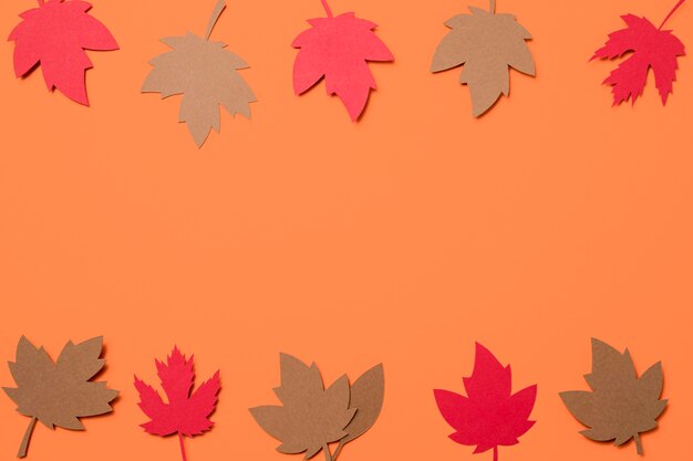 Flat lay paper autumn leaves on orange background with copy space