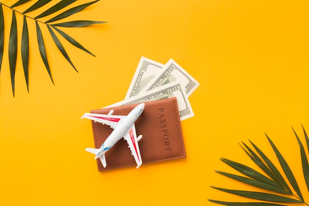 Flat lay of passport with and money and plane figurine on top