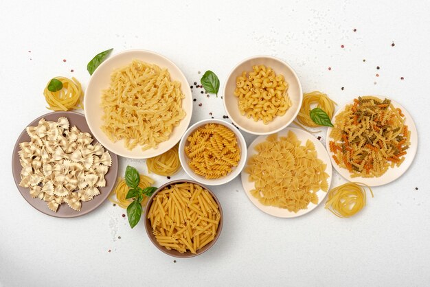 Flat lay of pasta in bowls on plain background