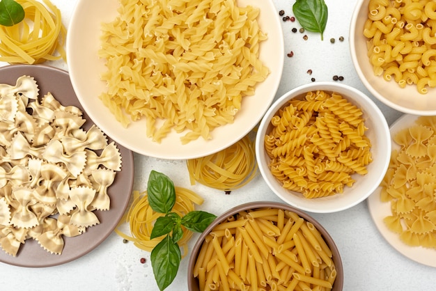 Flat lay of pasta in bowls on plain background
