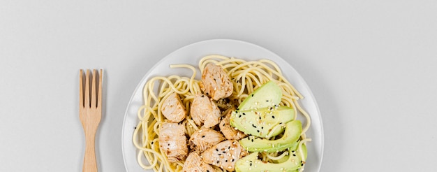 Flat lay of pasta with meat and avocado on plate