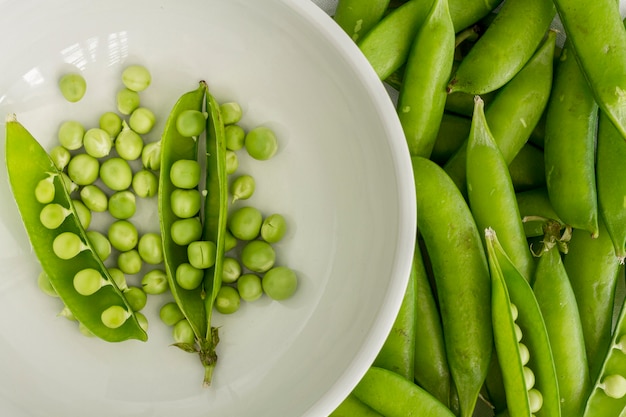 Flat lay pea pods with bowl