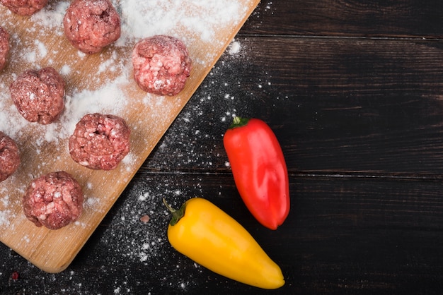 Flat lay peppers and meatballs on wooden board